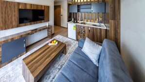 Un salon moderne avec un canapé gris, une table basse en bois et un téléviseur à écran plat fixé au mur.