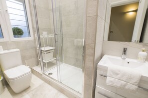 A bathroom with a glass-enclosed shower, a toilet, and a sink with a towel. - Westbourne Gardens by Lime Street (London)