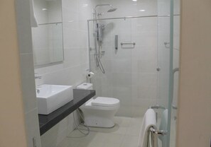 A modern bathroom with a glass-enclosed shower, a white sink, and a toilet.