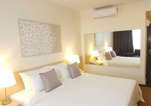 A hotel room with a large bed, two bedside lamps, a wall-mounted air conditioner, and a large mirror reflecting the room. - The View Hotel (Segamat)