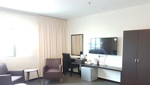A hotel room with a bed, a desk with a computer, a chair, a small table, a TV, and a wardrobe. - The View Hotel (Segamat)