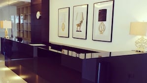 A modern reception area with a dark counter, a clock, and three framed artworks on the wall. - The View Hotel (Segamat)
