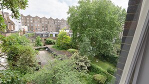 A courtyard with a small bridge, surrounded by trees and buildings. - Craven Hill by Lime Street (London)