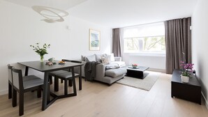 A modern living room with a dining table, grey sofa, and a coffee table. - Craven Hill by Lime Street (London)