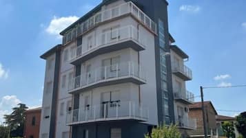 Un edificio a più piani con balconi, un tetto piano e cielo sereno.