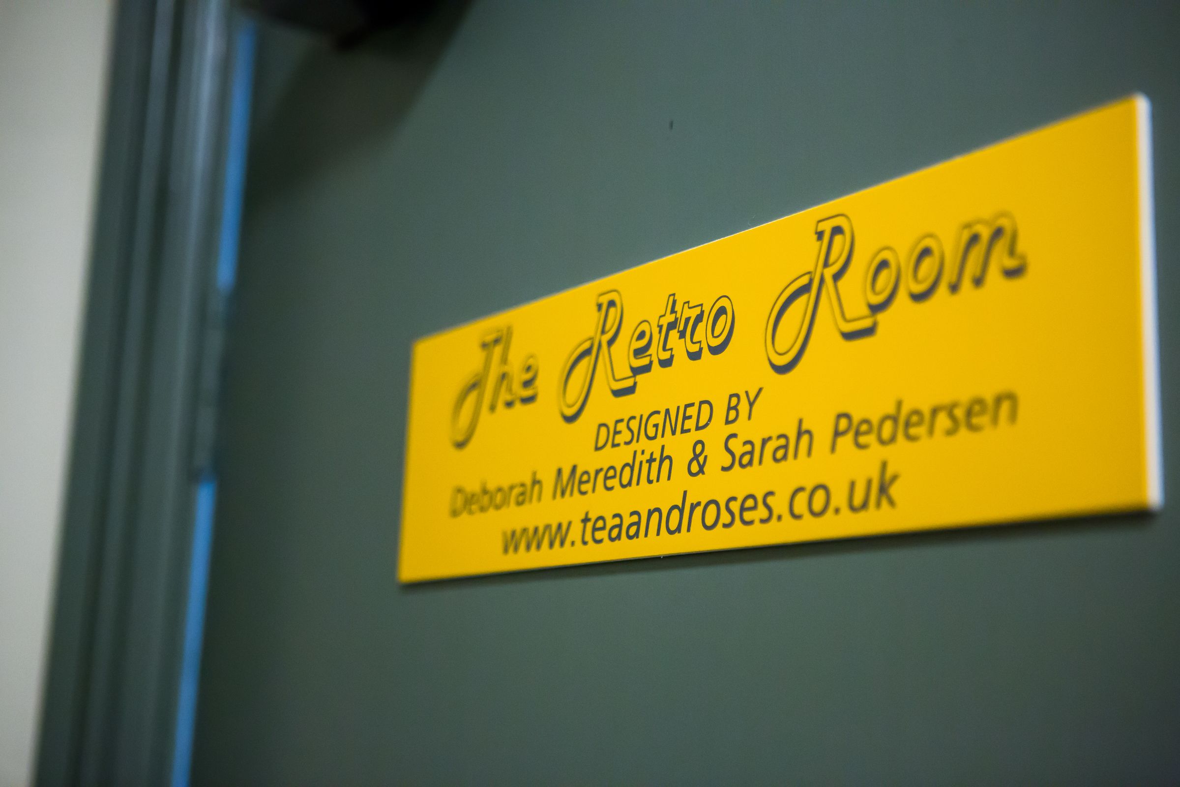 A yellow sign with the text "The Retro Room" and credits to designers Deborah Meredith & Sarah Pedersen.