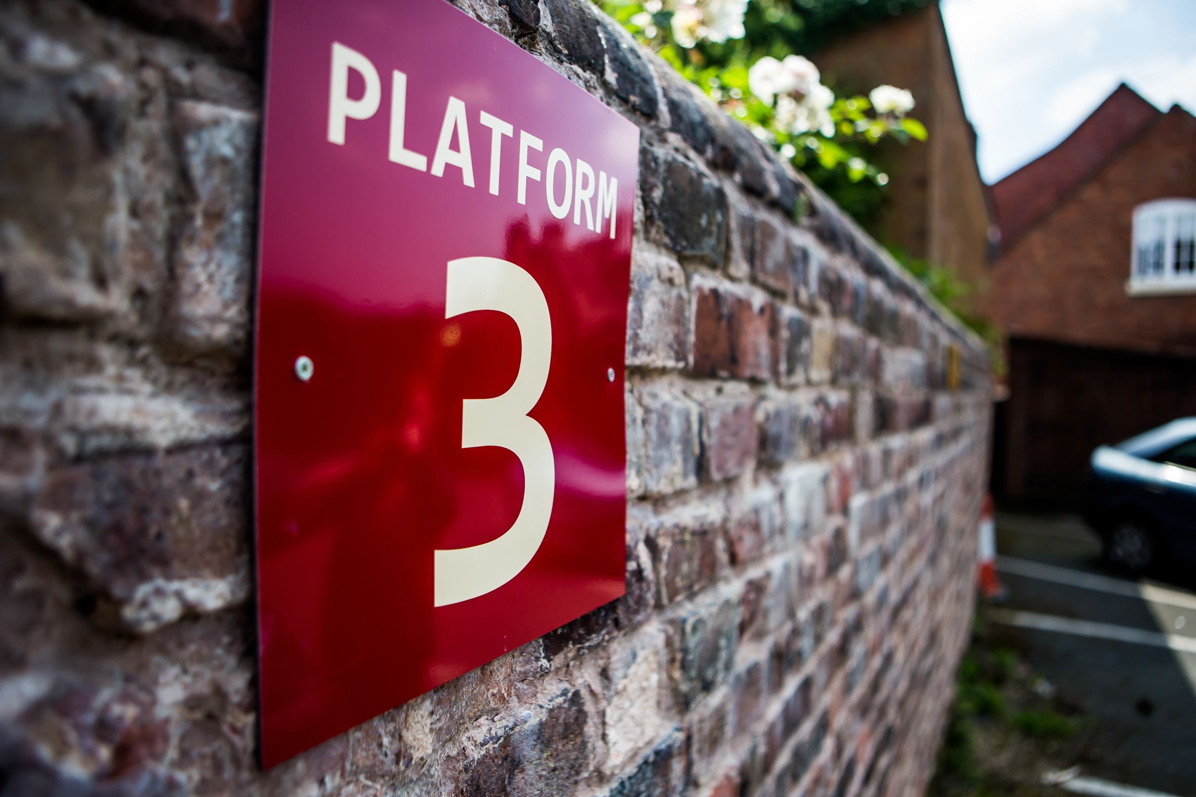 A red sign with the number 3 on a brick wall.