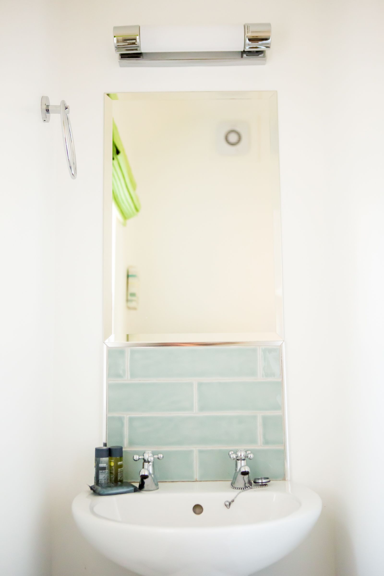 Une salle de bain avec un lavabo blanc, deux robinets et un miroir au-dessus.
