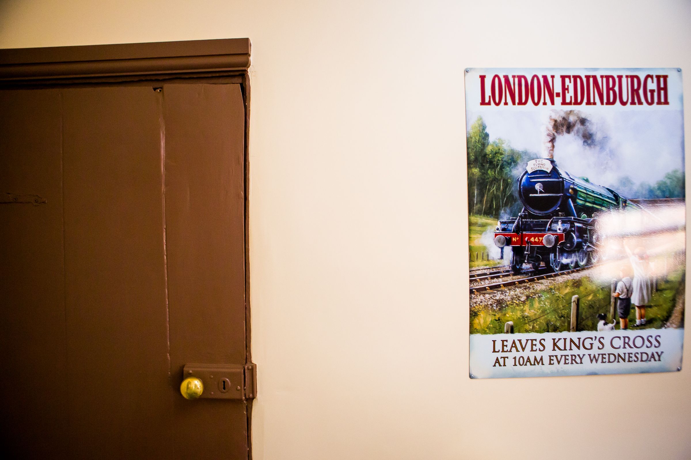 Una puerta con picaporte de latón y un cartel de un tren en la pared.