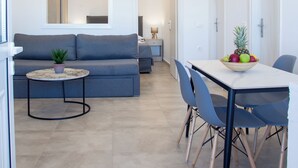 En moderne stue med en sofa, et spisebord med stole og et lille rundt bord med en plante.