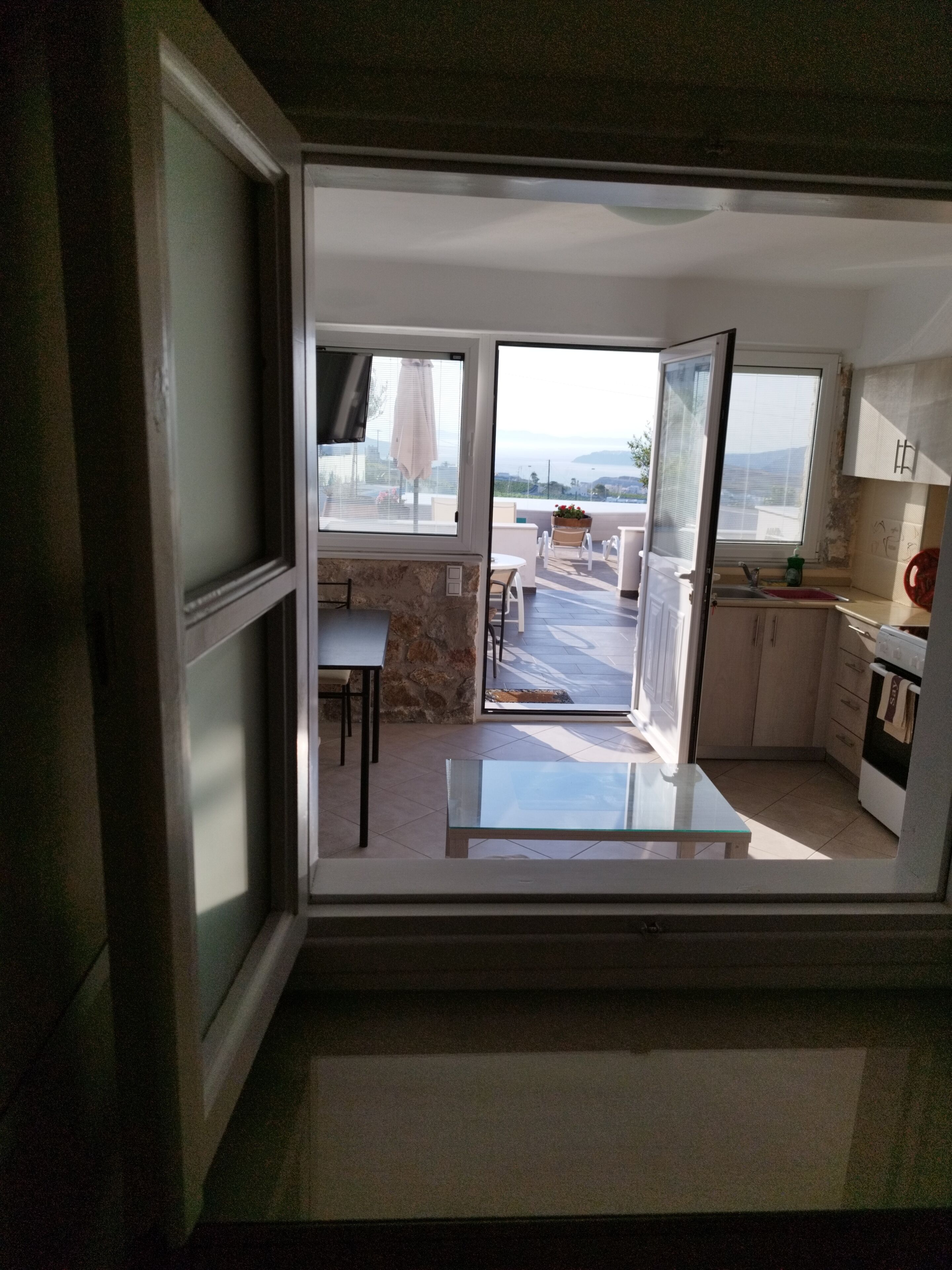 Una cocina moderna con vistas al exterior, un comedor con mesa y sillas, y una pequeña zona de estar con una mesa y sillas.