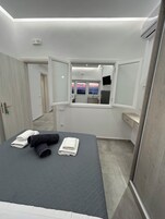 Un dormitorio moderno con una cama, un espejo grande y vistas al atardecer a través de la ventana.