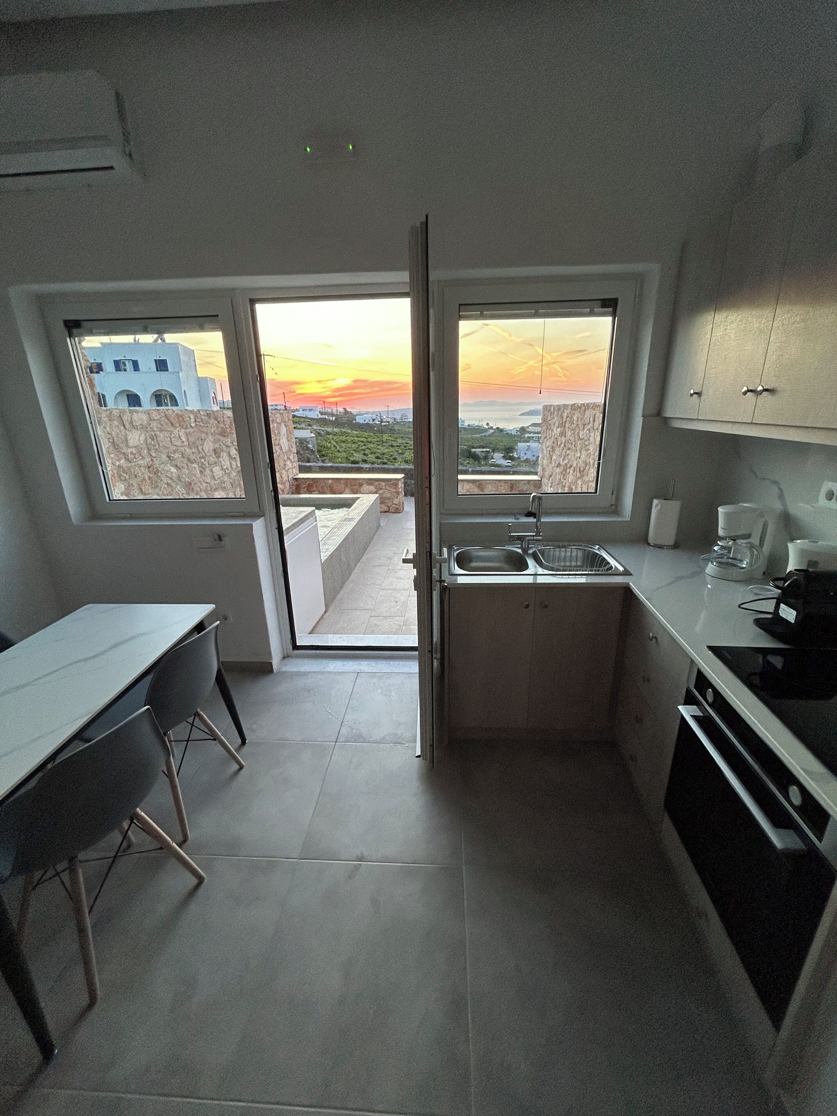 A compact kitchen with a view of the sunset, a dining area, and a small table.