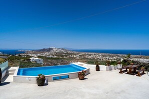 A rooftop pool with a view of the sea and distant hills. - Aroma Cavas (Santorini)