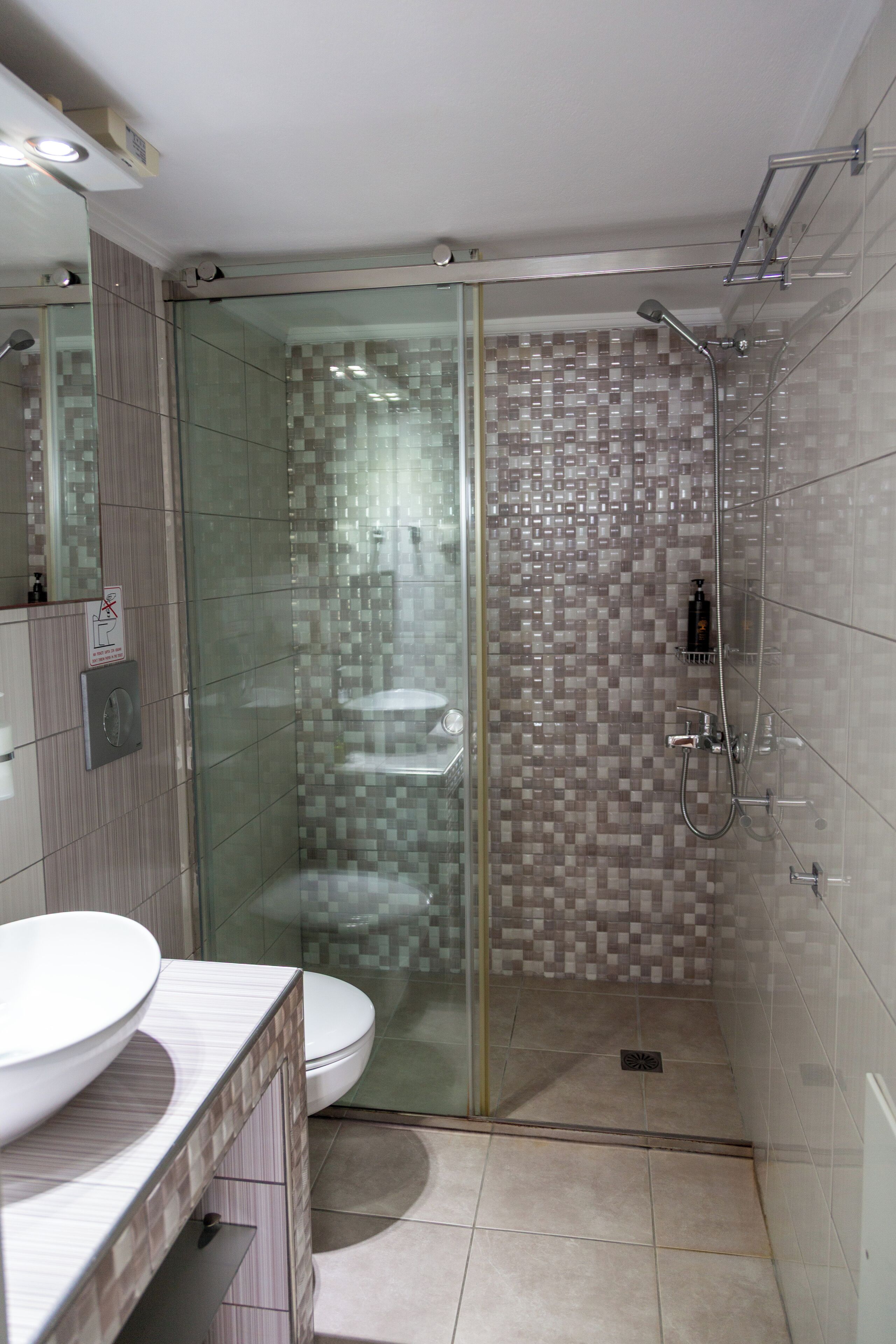 Une salle de bain moderne avec une douche à parois de verre, des toilettes et un lavabo doté d'un plan de travail en marbre.