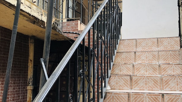 A staircase with metal railings and patterned tiles, leading to a balcony with a potted plant. - Mexica Apartment 20-30 min from the Airport (San Miguel Xalostoc)