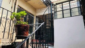 A balcony with a potted plant, a metal railing, and a staircase leading to an upper level. - Mexica Apartment 20-30 min from the Airport (San Miguel Xalostoc)