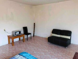 A cozy space with a wooden table, black chair, and sofa, featuring a microwave and patterned tiles.