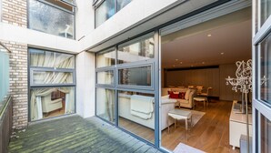 Un appartement moderne doté d’une porte en verre qui donne sur un espace de vie comprenant un canapé, une petite table et un lustre.