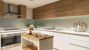 Une cuisine moderne avec des armoires blanches, un plan de travail en bois et un four encastré.