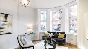 Una sala de estar moderna con un sofá, una mesa de centro y una mesita de vidrio con una lámpara.