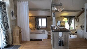 Une chambre rustique avec un lit en bois, un lustre et un mur en pierre.