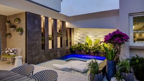 A modern outdoor pool area with lounge chairs, a hot tub, and various potted plants. - Trópica Beach Hotel (San Juan)