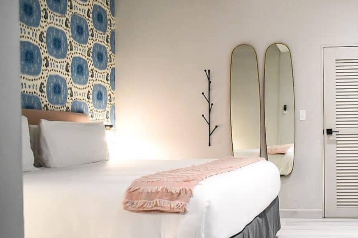 A bedroom with a bed, a wall-mounted branch decoration, and two mirrors.