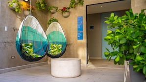 Un interior moderno con dos sillones colgantes, una planta en maceta y un cartel en la pared.
