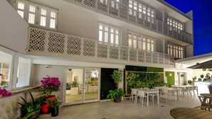 A multi-story hotel with balconies, outdoor seating, and a view of the night sky. - Trópica Beach Hotel (San Juan)