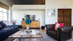 A living room with a sofa, a coffee table, a TV, and a wooden cabinet. - One Palace Gate (London)