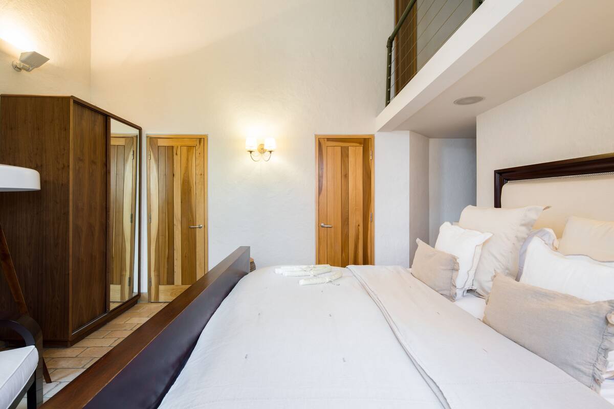 Un dormitorio con una cama grande, un armario de madera y un espejo.