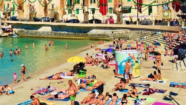 A beach with a historic church in the background. - Le Malte House St Julians (St. Julian's)