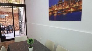 A conference room with a table, chairs, a potted plant, and a cityscape painting on the wall. - Le Malte House St Julians (St. Julian's)