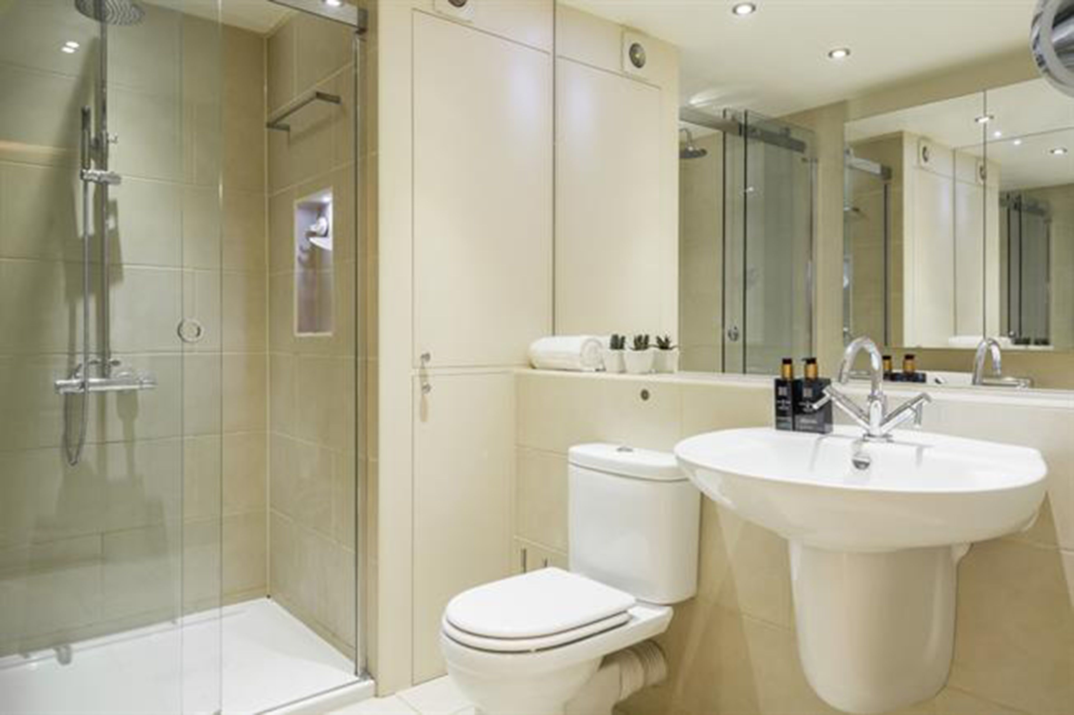 Un bagno moderno con doccia vetrata, un water e un lavandino con specchio sopra.