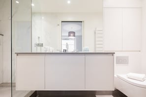 A modern bathroom with a glass-enclosed shower, a white vanity with a mirror, and a toilet.