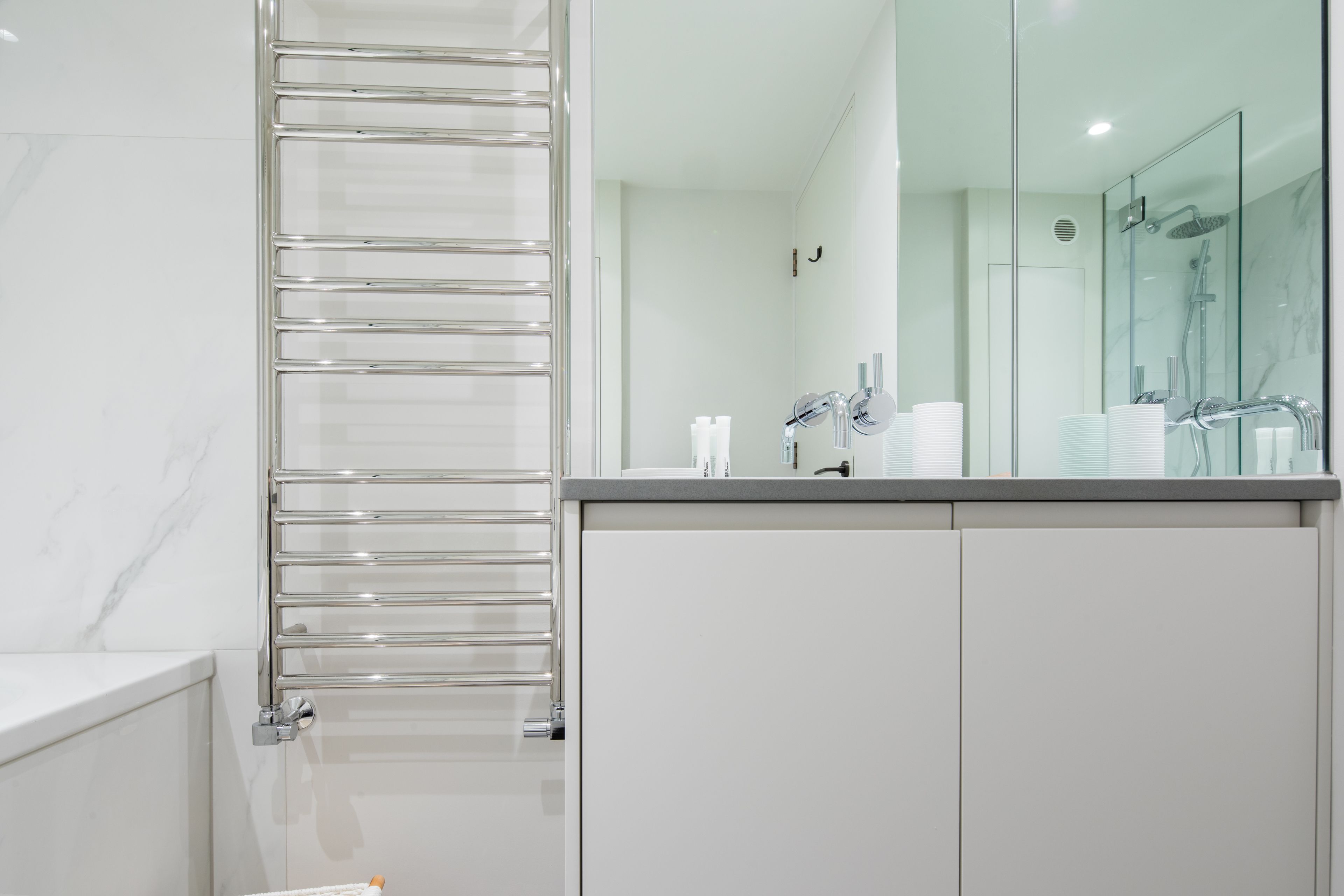 A modern bathroom with a glass shower enclosure, a glass shower door, and a chrome towel rack.