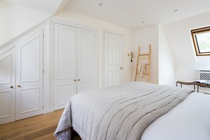 A bedroom with a large bed, white walls, and a wooden floor. - Cornwall Gardens by Lime Street (London)