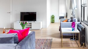 A modern living room with a flat-screen TV, grey sofa, and a coffee table. - Greek Street Penthouse (London)