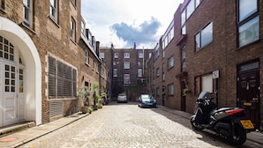 A narrow cobblestone street flanked by brick buildings with multiple windows and doors. - Richardsons Mews by Lime Street (London)