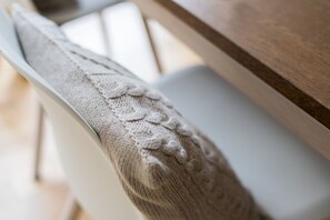 Detailaufnahme der Rückenlehne eines Stuhls mit einem gestrickten Muster.