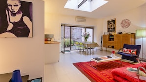 A modern living room with a skylight, a dining area with a table and chairs, and a red sofa. - Rome as you feel - Selci Apartment (Rome)