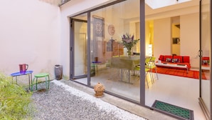 A modern living room with a glass door leading to a dining area, a small table with chairs, and a red sofa. - Rome as you feel - Selci Apartment (Rome)