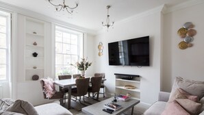 A modern living room with a sofa, coffee table, TV, and dining area. - Star Street by Lime Street (London)