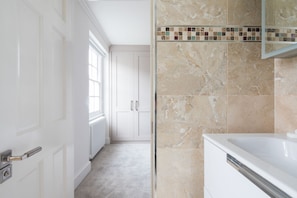 A modern bathroom with a bathtub, a shower area, and a tiled backsplash.