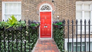A red door with the number 99, a brick wall, and a black iron fence with greenery. - Star Street by Lime Street (London)