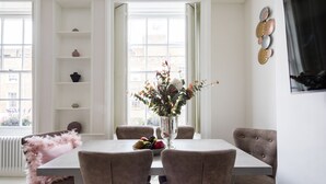 A dining area with a table, chairs, a vase with flowers, and a fruit bowl. - Star Street by Lime Street (London)