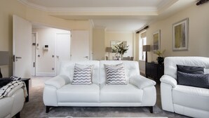 Ein modernes Wohnzimmer mit einem weißen Ledersofa, einem Couchtisch und einem Essbereich im Hintergrund.