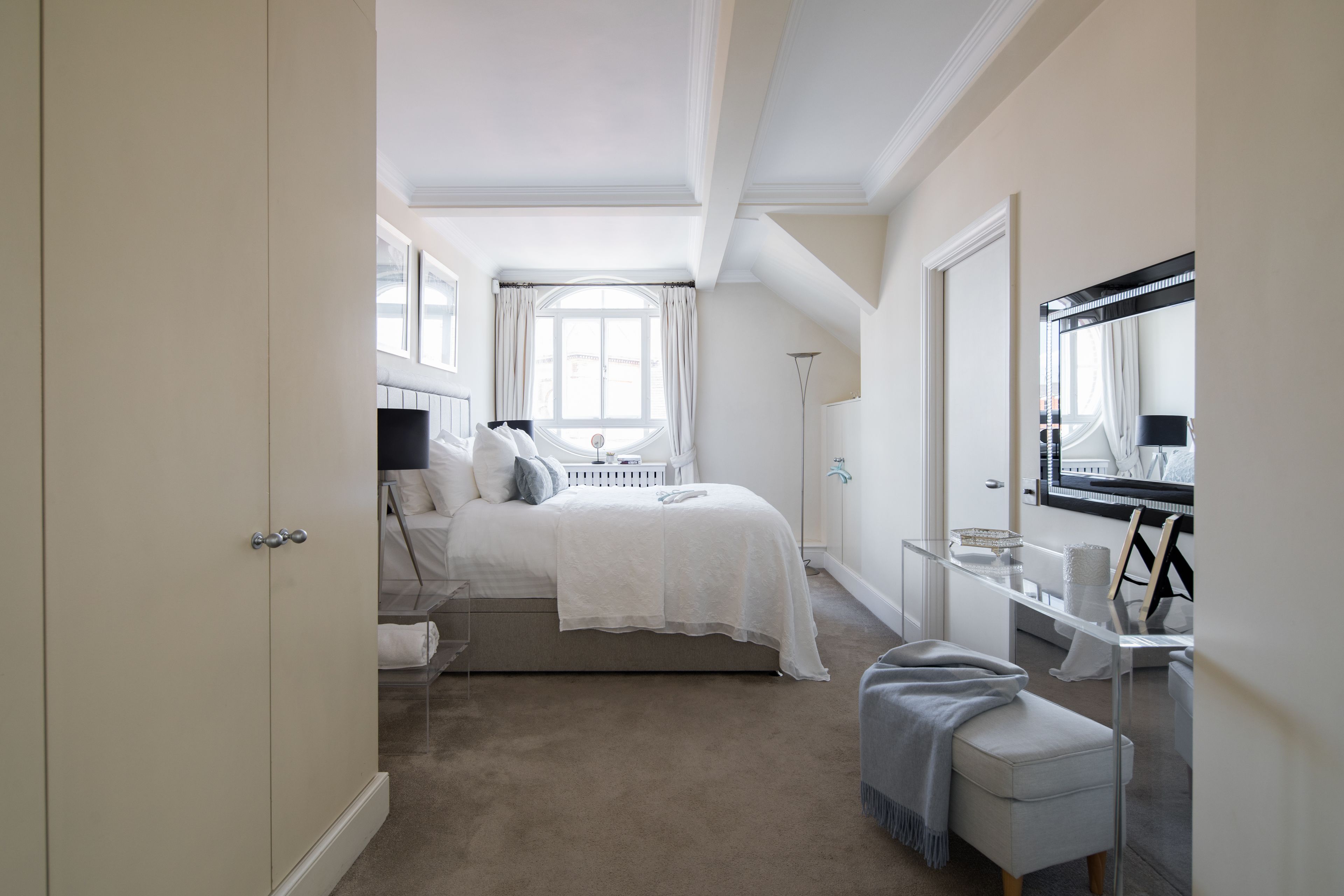 Une chambre à coucher avec un lit, une table de chevet et un grand miroir.