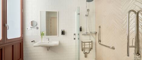A modern bathroom with a glass-enclosed shower, a sink with a mirror, and a patterned floor.